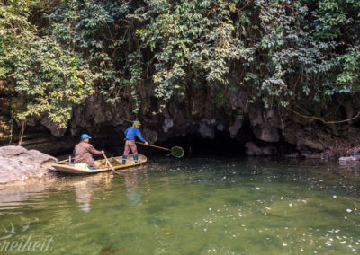 Zwei Männer beim Saubermachen vorm Höhleneingang