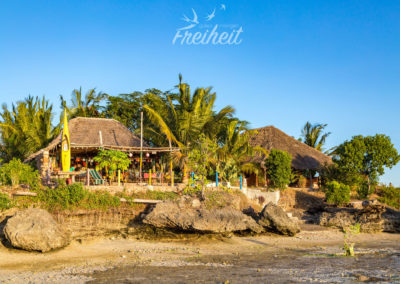 Links das Restaurant, rechts ein Familienbungalow. Bei Flut reicht das Wasser bis an die Felsen